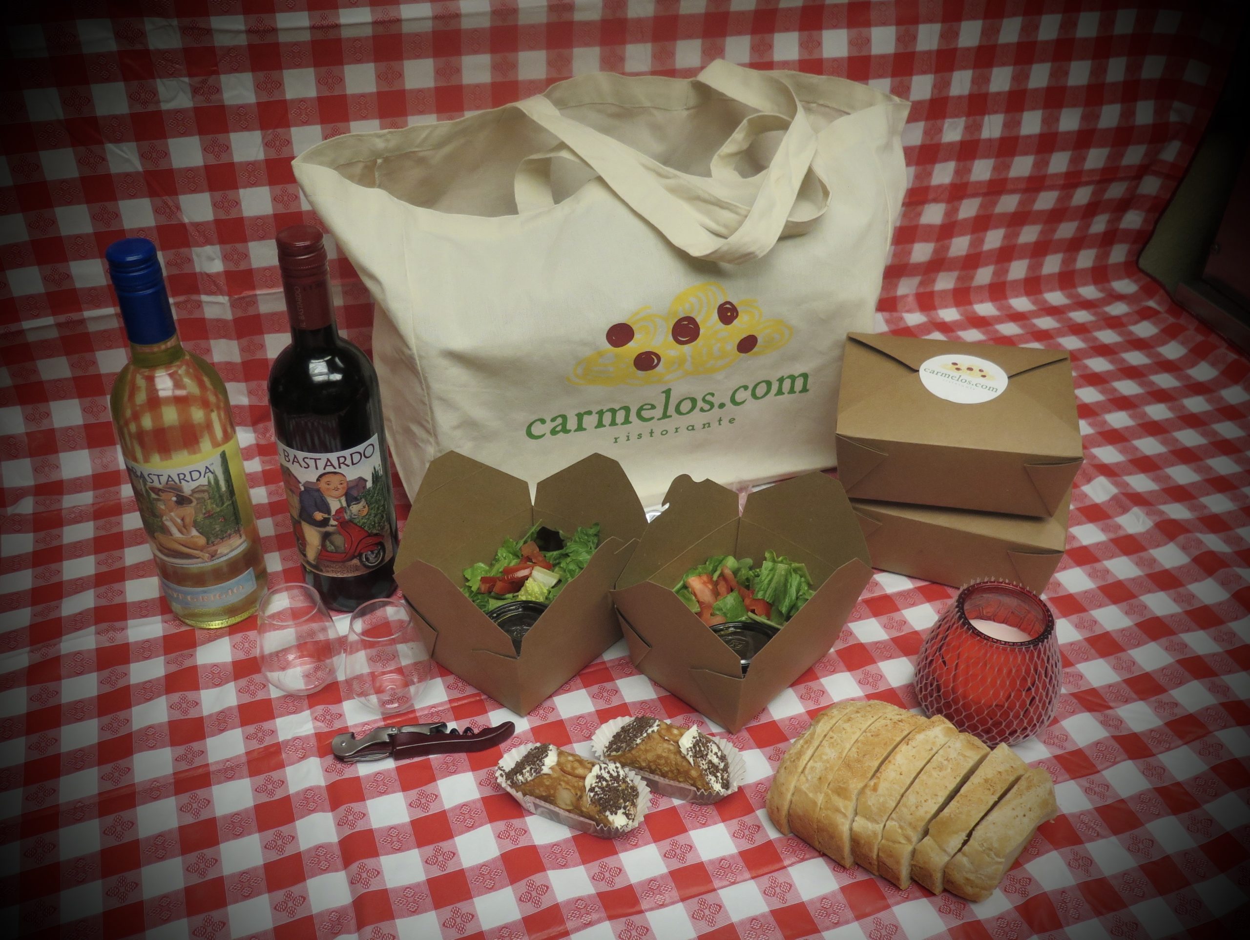 Picnic kit with packed food, wine bottle, and canvas carrying bag